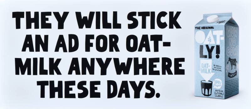 A poster with black text on a white background next to a carton of oatmilk