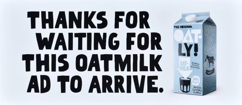 A poster with black text on a white background next to a carton of oatmilk