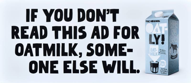 A poster with black text on a white background next to a carton of oatmilk