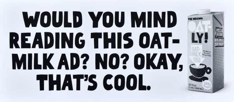 A poster with black text on a white background next to a carton of oatmilk