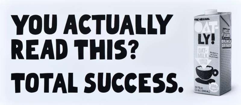 A poster with black text on a white background next to a carton of oatmilk