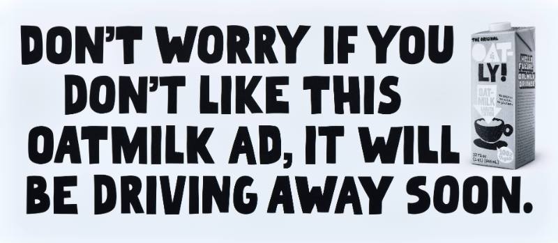 A poster with black text on a white background next to a carton of oatmilk