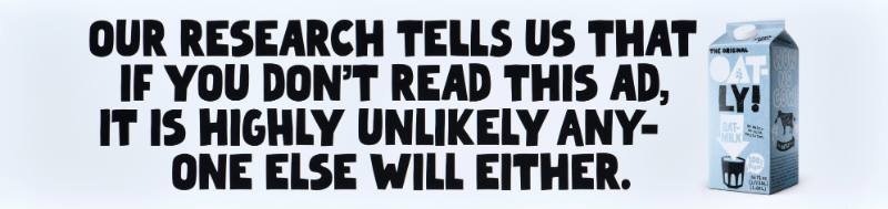 A poster with black text on a white background next to a carton of oatmilk