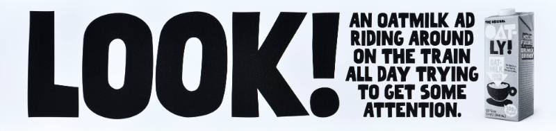 A poster with black text on a white background next to a carton of oatmilk