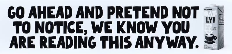 A poster with black text on a white background next to a carton of oatmilk