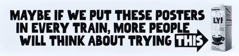 A poster with black text on a white background next to a carton of oatmilk