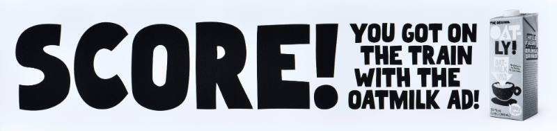 A poster with black text on a white background next to a carton of oatmilk