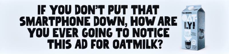 A poster with black text on a white background next to a carton of oatmilk