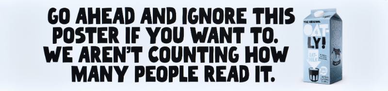 A poster with black text on a white background next to a carton of oatmilk