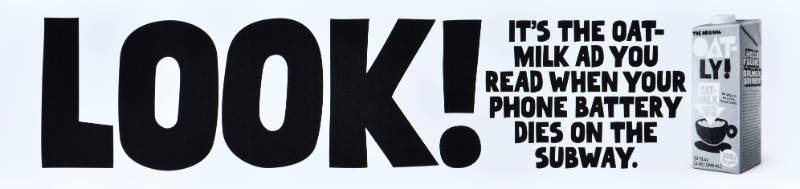 A poster with black text on a white background next to a carton of oatmilk