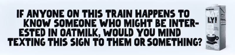 A poster with black text on a white background next to a carton of oatmilk