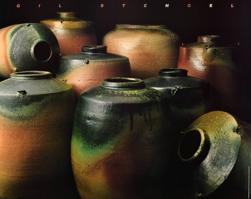 A poster of a pile of brown and green ceramic pots on a black background