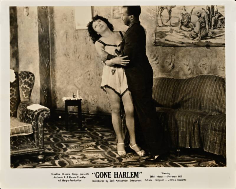 A printed card with a black and white photograph of a Black man embracing a Black women in underwear