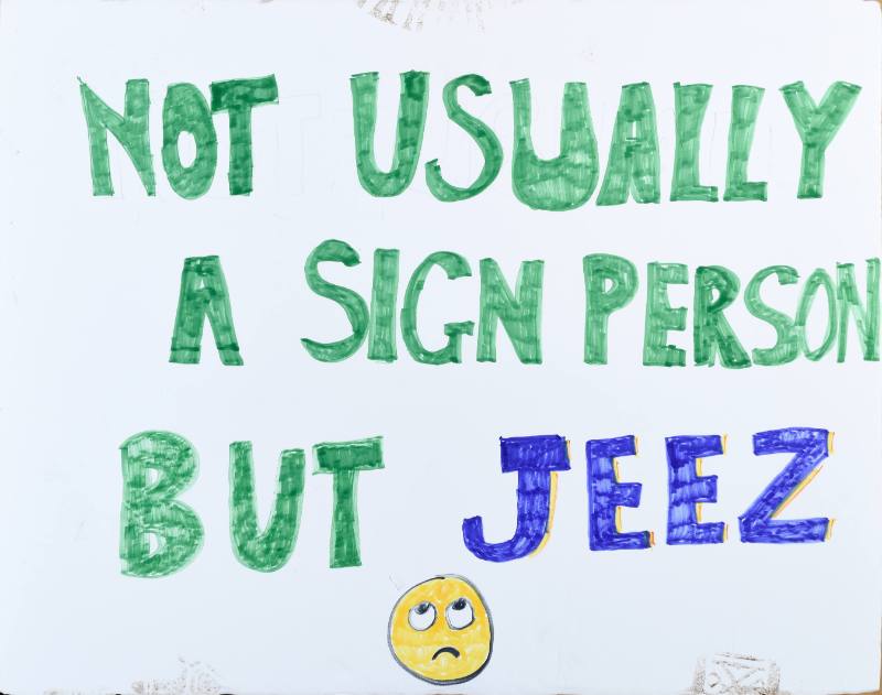 A poster with green text and a yellow frowning face on a white background