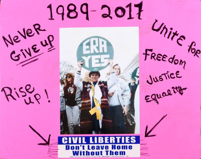A pink poster with black text and a photograph of women protesting for the Equal Rights Amendment in 1989