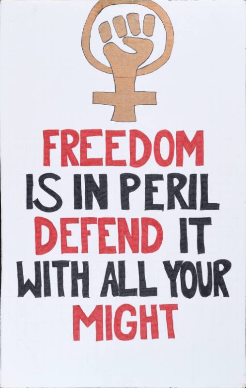 A poster with red and black text and a gold fist on a white background