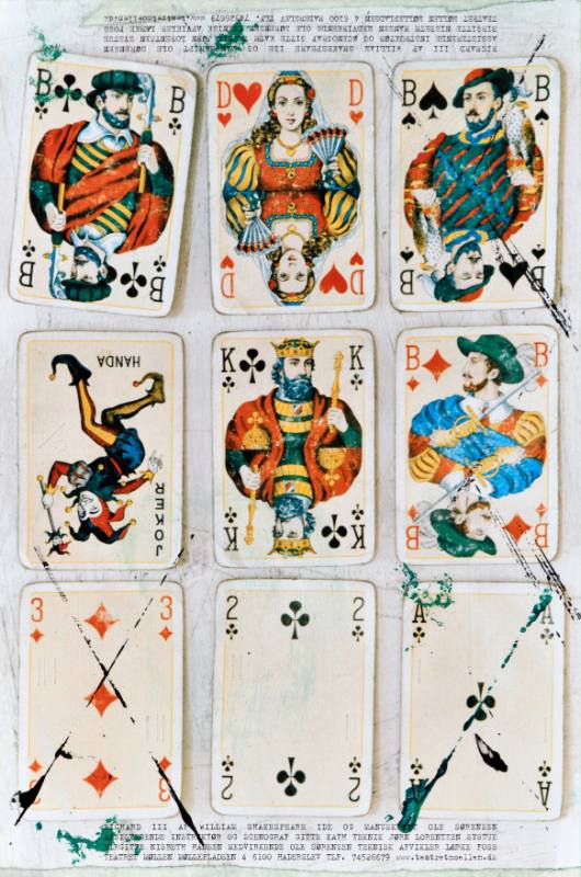 A poster of 9 playing cards on top of a play script with ink stains and scratches on each card.
