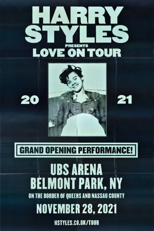 A poster of a green image of a young Harry Styles laying down with suspenders and a button up shirt.